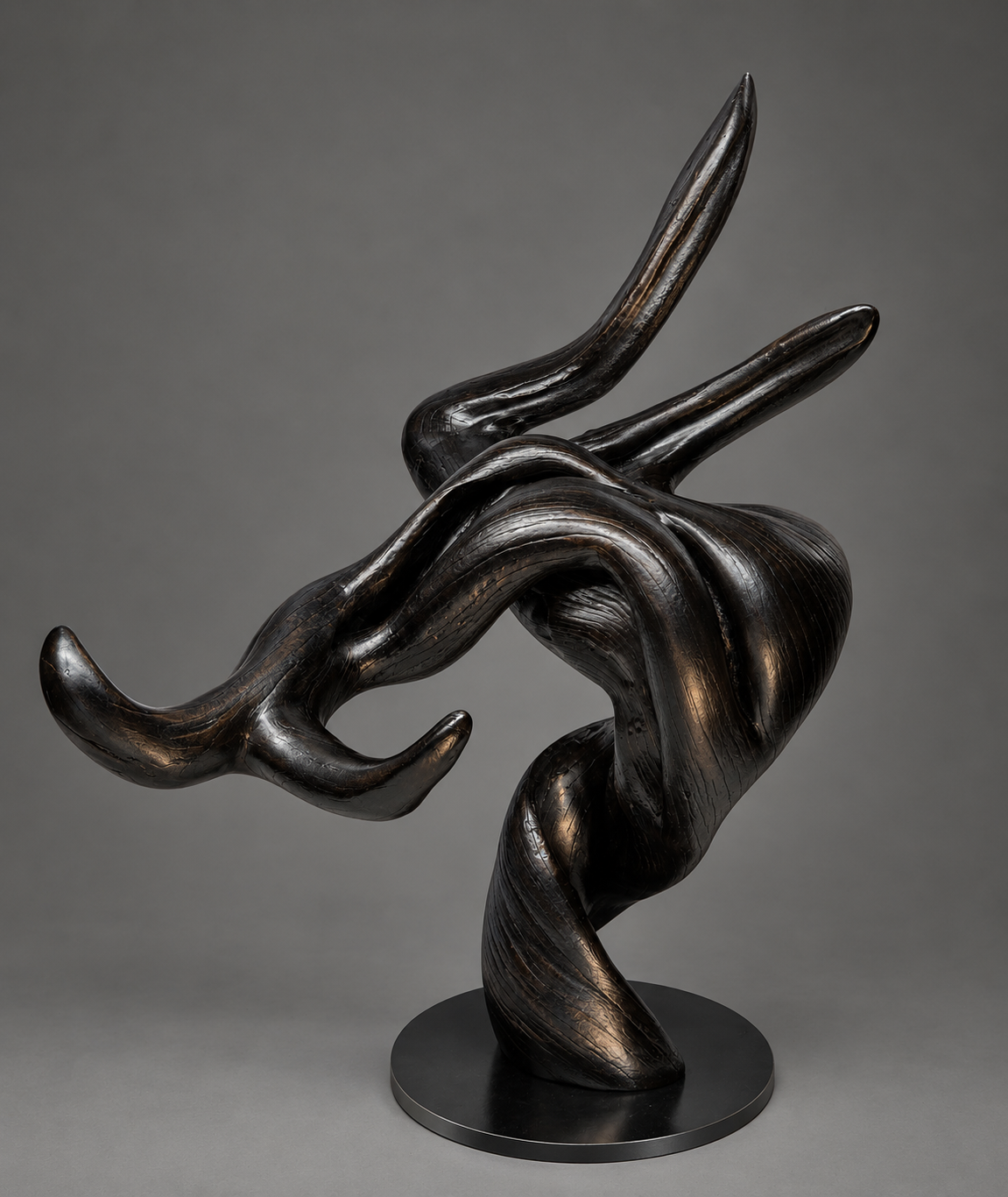 Abstract black juniper wood sculpture with flowing curved lines mounted on a round steel base. Made of torched juniper wood.